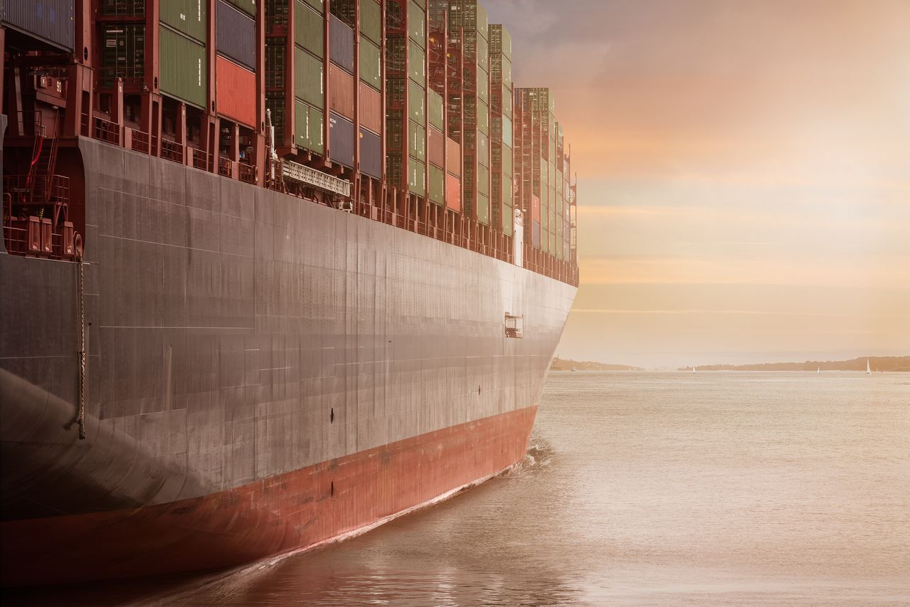 Container ship carrying export cargo at sunset