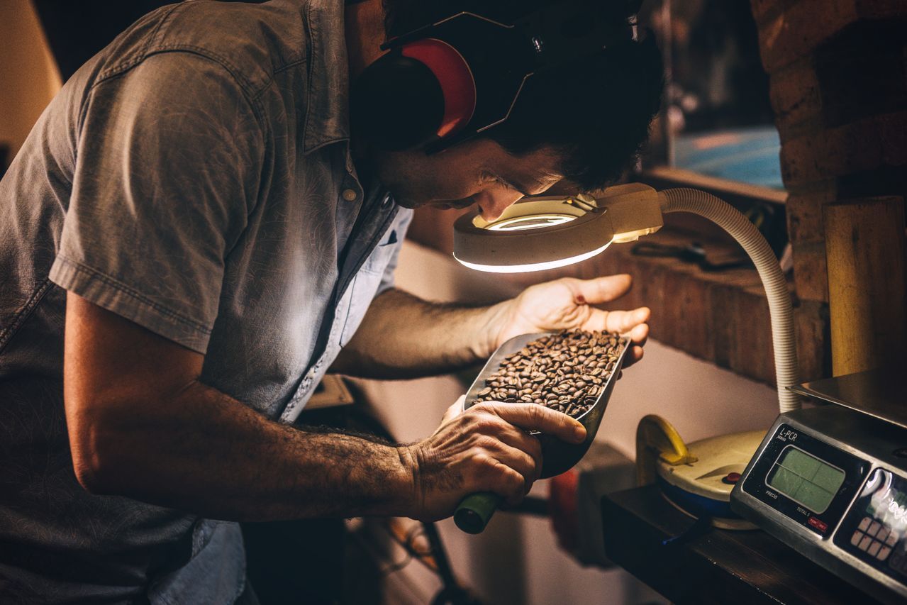 Inspector examining a commodity sample under magnification beside a scale